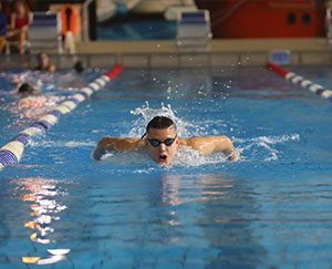 The photo shows a young boy wearing swimming goggles in a pool
