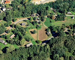 Fotografia z lotu ptaka przedstawia tereny zielone. Widoczne są drzewa, łąki oraz zabudowania skansenu w Chorzowie.