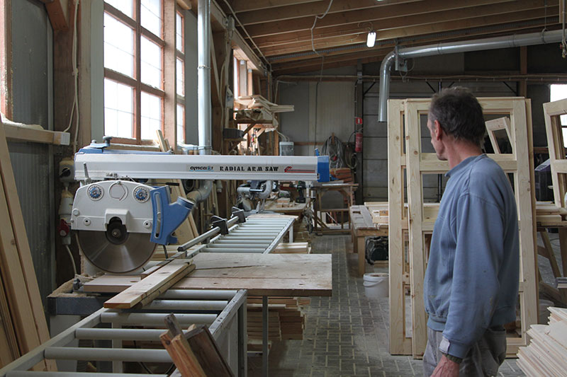 Fotografia przedstawia pracownika zakładu stolarskiego przy jednej z pilarek.