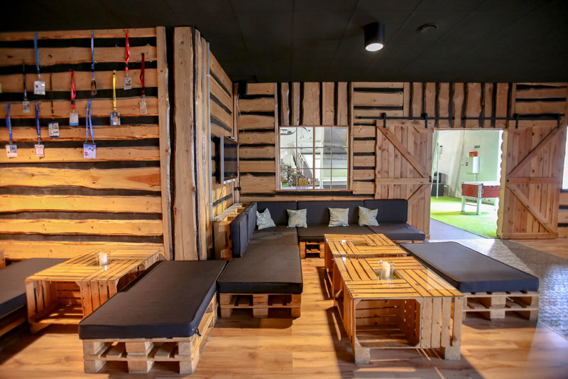 Fotografia przedstawia kawiarnię, gdzie ściany, stoliki i ławeczki zrobione są z drewna.