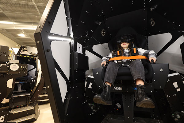 The photo shows a child sitting in a special capsule, with virtual reality goggles on his face.