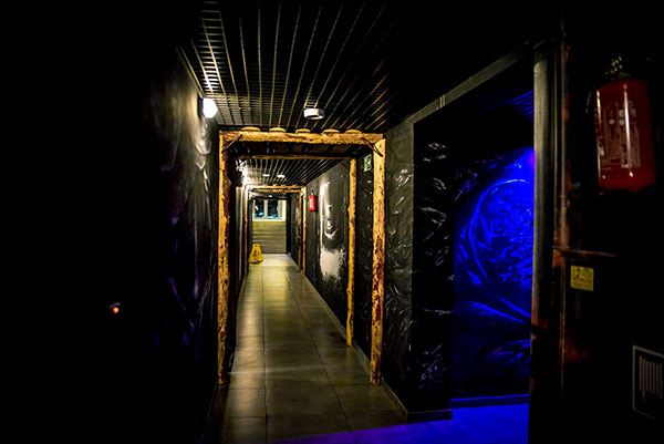 Na zdjęciu widzimy korytarz stylizowany na chodnik w kopalni. Jest ciemny, co kilka metrów widoczne są górnicze obudowy z drewna.