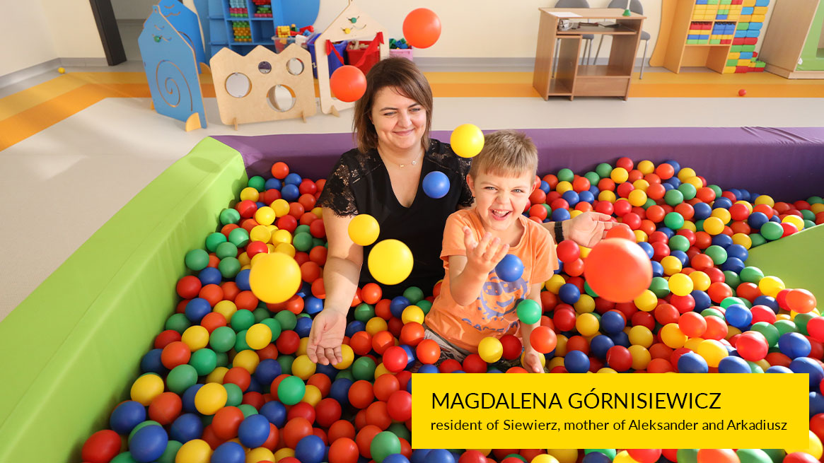 The photograph shows a mother and child in a pool of colorful balls. Several of them are in the air.