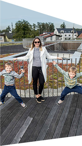 Fotografia przedstawia Paulinę Gaik, ze swoimi dziećmi: bliźniakami Igorem i Aleksandrem, na tarasie urządzonym na dachu przedszkola.