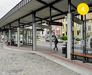 The photograph shows a part of the bus station in Cieszyn. You can see roofed bus stations. There are young passengers sitting and waiting for the bus. The photo was taken by Dominik Wójcik.