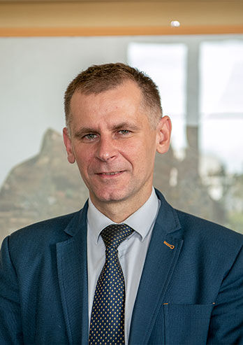The photograph shows Rafał Piotrowski, acting Head of the Education Department of Częstochowa City Hall. He is a middle-aged man and he is wearing a suit and a tie. The photo was taken by Maciej Motylewski.