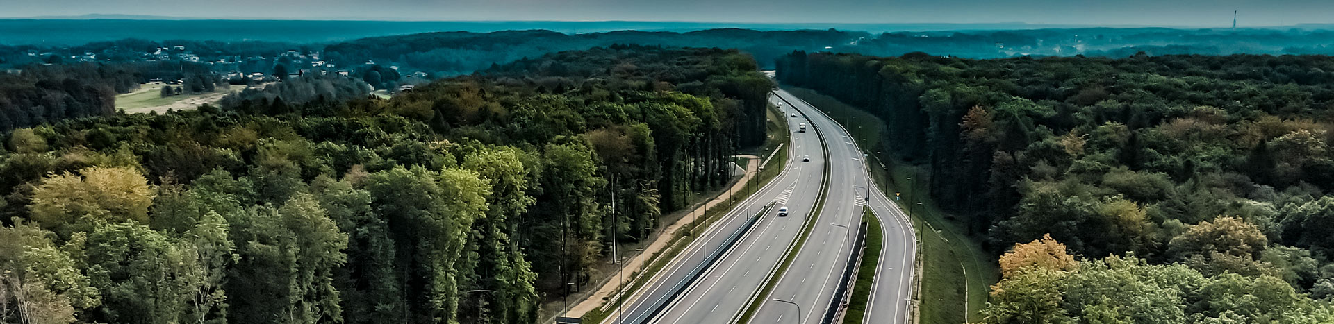 The photograph shows a fragment of the Racibórz-Pszczyna road running through Rybnik. You can see the new route with two lanes both ways and entries and exits. There are trees all around. A panorama is also visible. The photo was taken by Maciej Motylewski.