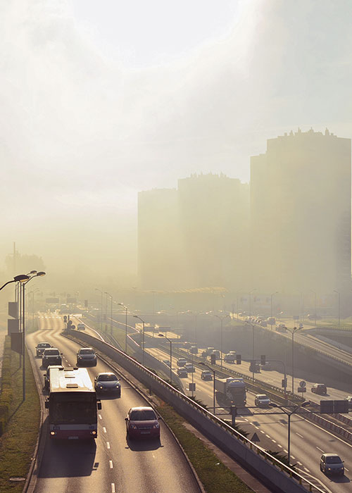 Zdjęcie przedstawia metropolię: liczne wieżowce, samochody w ruchu miejskim, wiadukty, wielopasmowe drogi. Część budynków słabo widoczna z powodu smogu.