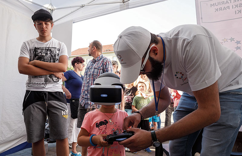 Dziewczynka z dżojstikiem w ręku i w okularach VR uczy się grać w wirtualnej rzeczywistości