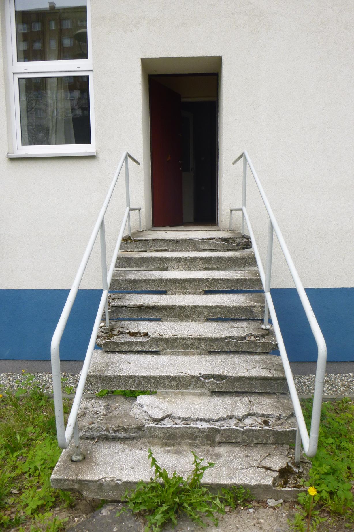 Wejście do budynku przy ulicy Jagiellońskiej przed renowacją - zniszczone schody, barierki i drzwi niezapewniające bezpieczeństwa dzieciom